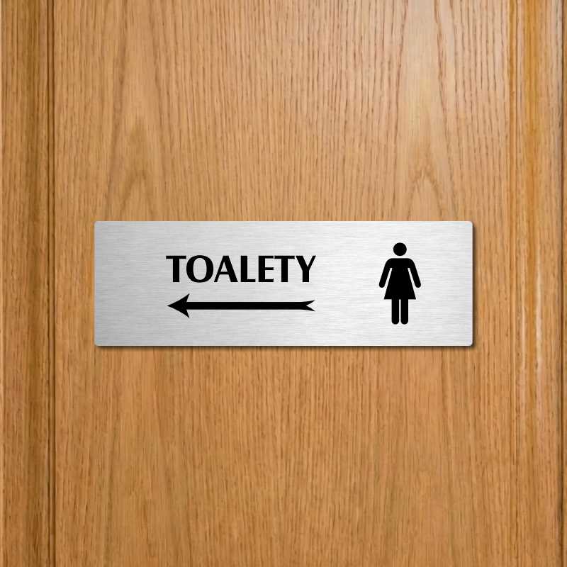 Toalety vlevo ženy, 240x79mm, zlatá popiska s okrasným rámečkem  